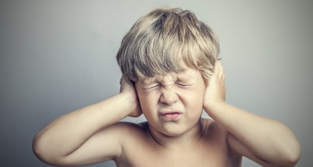 boy with closed ears on a gray background